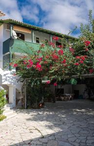Un edificio con un mazzo di fiori rosa sopra di Pansion Vasso a Ayios Nikitas