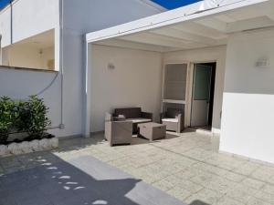 Casa blanca con patio con sofá y sillas en Alvaro Holiday Home, en Torre Lapillo