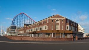 ein großes Backsteingebäude mit einem Riesenrad im Hintergrund in der Unterkunft Coastal Plaza in Blackpool