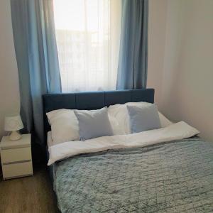 科沃布熱格的住宿－Apartament Azzurro Porta Mare Baltica Kołobrzeg，一张带枕头和窗户的蓝色床头板的床