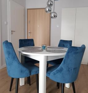 科沃布熱格的住宿－Apartament Azzurro Porta Mare Baltica Kołobrzeg，周围设有蓝色椅子的白色桌子