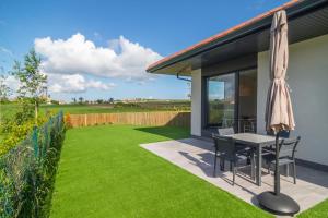 a patio with a table and chairs and a lawn at OCEANSUITESLANGRE in Galizano