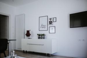 - un salon blanc avec une télévision et une commode blanche dans l'établissement L'Anfora Residence, à Roseto degli Abruzzi