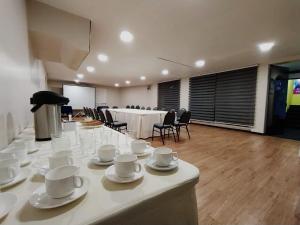 ein Zimmer mit einem langen Tisch mit weißen Tassen und Untertassen in der Unterkunft Pan American Hotel in La Paz