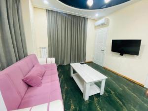uma sala de estar com um sofá rosa e uma mesa em Pirosmani Apartment em Batumi