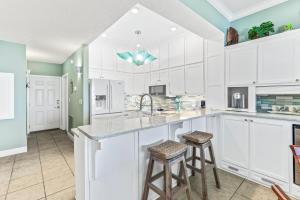 a kitchen with white cabinets and two bar stools at Windemere Beachfront Condo 1503 in Perdido Key