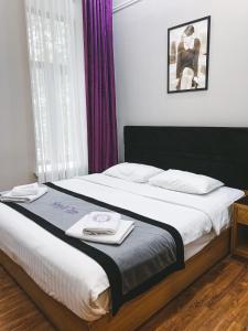 a bedroom with a large bed with purple curtains at Sleepy Tom Boutique Hotel in Moscow