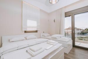 a white bedroom with two beds and a large window at Villa Kyros in Korinos