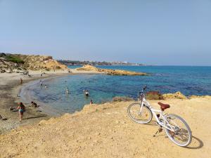 a bike parked on a beach with people in the water at Estrella Del Mar Tranquil and spacious villa, convenient location 3-5 mins' walk to all amenities in Villacosta