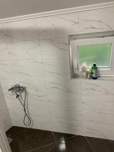 a bathroom with a white tiled wall with a window at Apartman Bojanić in Trebinje