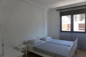 een witte slaapkamer met een bed en een raam bij APARTMAN AURORA in Trebinje +29 foto's