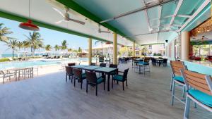 a patio with tables and chairs next to a pool at The Grand Caymanian Resort in George Town