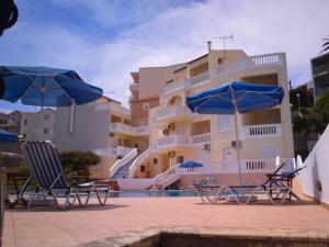 two chairs and umbrellas in front of a building at Kalimera Hotel in Agia Marina Nea Kydonias