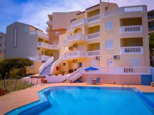 a building with a swimming pool in front of a building at Kalimera Hotel in Agia Marina Nea Kydonias