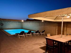 a swimming pool with chairs and a table and an umbrella at Mejda Farmhouse in Victoria
