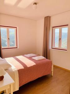 a bedroom with a bed and two windows at Terraços do Távora in Tabuaço