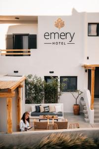 a woman sitting on a patio in front of a hotel at Emery Hotel in Naxos Chora