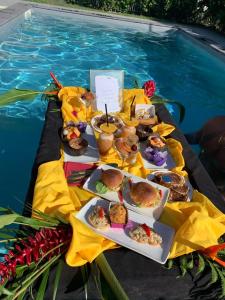 a table with plates of food next to a swimming pool at Gîtes de Corneille, Bungalow Little Banania in Le Moule +38 photos