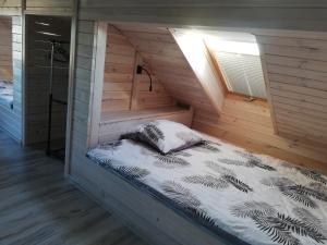 łóżko w drewnianym domku z oknem w obiekcie PAKLADA 3 Pokój typu studio w mieście Karsin