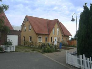 uma casa amarela com um telhado vermelho e uma cerca branca em Balm Haus Am Balmer See Haus 1 WBH1 em Balm