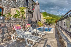 eine Terrasse mit 2 Stühlen und einem Sonnenschirm neben einem Pool in der Unterkunft Villa Old Olive 2 in Budva