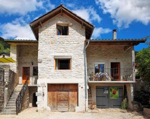 een groot stenen huis met een deur en een balkon bij La Belle Rivière in Bolozon