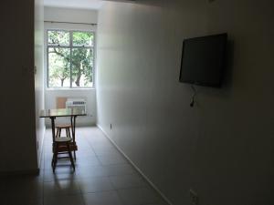 Habitación con mesa y TV en la pared. en Apartamento Barata Ribeiro, en Río de Janeiro