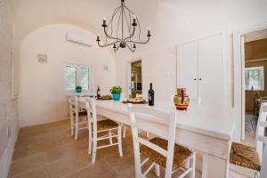 una cocina blanca con una larga mesa y sillas blancas en Villa Saracena, en Ostuni