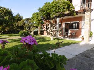 a house with purple flowers in the yard at Genari Beach Apartments in Levendokhórion