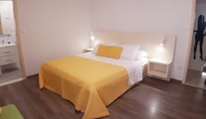 a bedroom with a bed with a yellow blanket on it at House Merlin in Baška Voda