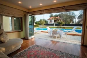 Una sala de estar con mesa y sillas y una piscina. en Villa in Esposende, en Esposende