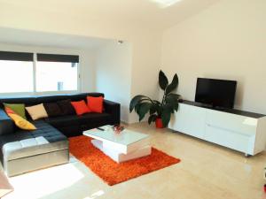 a living room with a black couch and a tv at House Merlin in Baška Voda