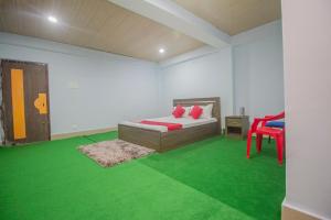 a room with a bed and a red chair and green carpet at OYO Brikcha Mukhia Home Stay in Pelling