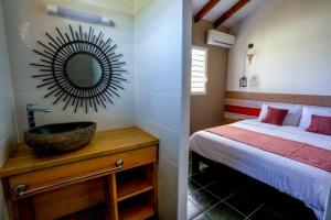 a bedroom with a bed and a sink and a mirror at Kâz corail in Sainte-Anne