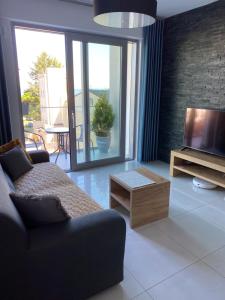 salon z kanapą i telewizorem w obiekcie MIĘDZYZDROJE,BALTICUS PROMENADA GWIAZD 14, Apartament z odrębnym salonem i sypialnią z Widokiem na morze w mieście Międzyzdroje