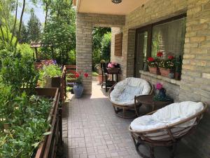 eine Terrasse mit 2 Stühlen, einem Tisch und Blumen in der Unterkunft Tulipán Apartman in Eger