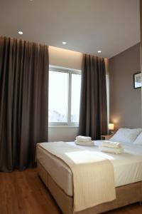 sypialnia z 2 łóżkami i dużym oknem w obiekcie Mood Athens Luxury Apartments and Suites w Atenach