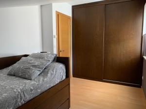 1 dormitorio con 1 cama y un gran armario de madera en Apartamento Praia de Quenxe, en Corcubión