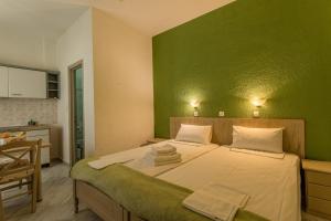 1 dormitorio con 1 cama grande y pared verde en Niriides Apartments, en Stoupa