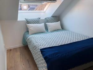 um pequeno quarto com uma cama com lençóis azuis e uma janela em Nouveau ! Appartement loft hyper centre Bayeux em Bayeux