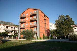 un edificio de apartamentos naranja con un árbol delante de él en VilaElenaMarko en Budva