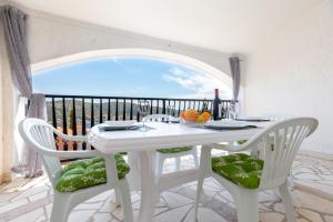 a white table and chairs with a view of the ocean at Apartments Villa Maja in Rogoznica