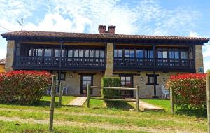 a house with a black balcony and red flowers at El Mirador de Sorribes in Sevares