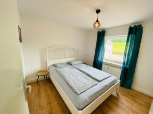 a bedroom with a bed with blue curtains and a window at Auszeit-Eifel „Eifelhorst“ in Willwerscheid