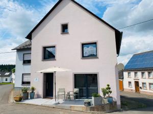 a white house with a table and an umbrella at Auszeit-Eifel „Eifelhorst“ in Willwerscheid