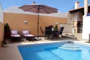 a patio with a table and an umbrella next to a pool at Castelinho Carrascal Sintra Summer Apt & Heated Pool in Sintra