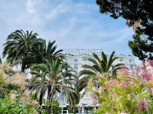 a white building with palm trees in front of it at La Rotonde YourHostHelper in Cannes