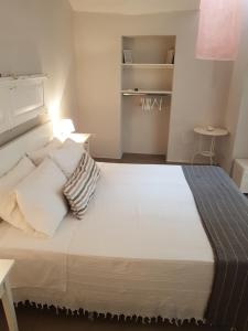 1 dormitorio con 1 cama grande con sábanas y almohadas blancas en CASETTE BRIGANTI - monolocali indipendenti con angolo cottura en Gallipoli