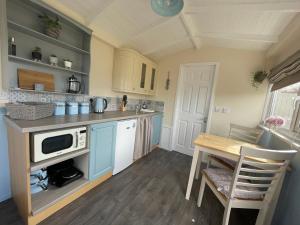 a kitchen with blue cabinets and a table with a microwave at Kevara Shepherds Hut in Finstown