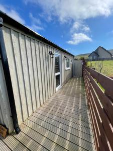 a wooden boardwalk leading to a building with a fence at Kevara Shepherds Hut in Finstown